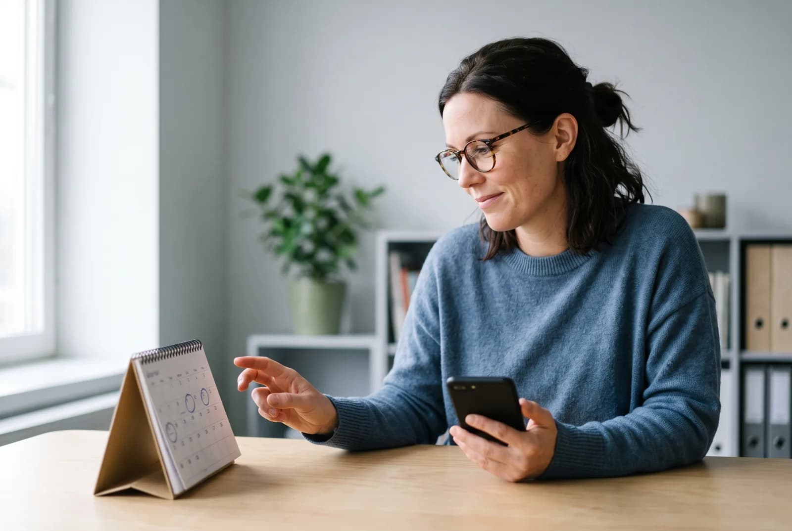 Ekonom med mobil i handen tittar på en bordskalender
